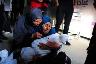 Seorang perempuan Palestina mengendong jenazah seorang anak yang tewas dalam pemboman Israel, di sebuah klinik kesehatan di kawasan Tel al-Sultan di Rafah, Jalur Gaza selatan, Minggu 26 Mei 2024.