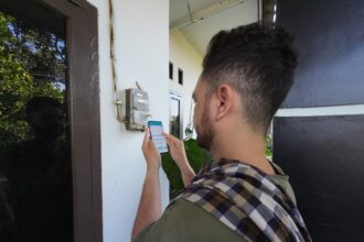 Alex (30) sedang melakukan pengisian token listrik melalui aplikasi PLN Mobile sambil mengecek berbagai fitur di aplikasi PLN Mobile.