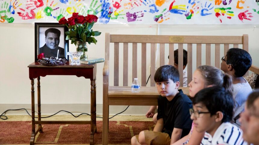 Anak-anak duduk di samping foto Muhammad Ali yang dipajang selama acar doa bersama di Louisville, Kentucky pada 5 Juni 2016 Foto: AP