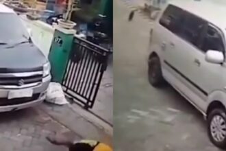 Pria berkaus kuning menenteng pistol kemudian menembak bagian bawah mobil yang parkir di sebuah rumah menembak mati kucing. Foto: X, @banyulangit_ (tangkap layar)