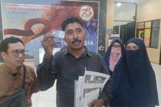 Pengacara korban penipuan, Muhammad Tasrif Tuasamu (tengah) mendampingi para kliennya menunjukkan kartu ATM bank ternama sebagai bukti di Mapolres Metro Jakarta Timur, Selasa (16/7/2024) sore. Foto: Joesvicar Iqbal/dok/ipol.id