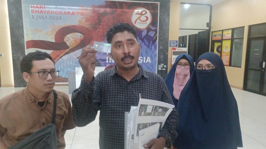 Pengacara korban penipuan, Muhammad Tasrif Tuasamu (tengah) mendampingi para kliennya menunjukkan kartu ATM bank ternama sebagai bukti di Mapolres Metro Jakarta Timur, Selasa (16/7/2024) sore. Foto: Joesvicar Iqbal/dok/ipol.id