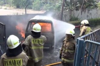 Sejumlah petugas Damkar memadamkan kobaran api yang membesar pada satu unit minibus yang membawa lima jerigen berisi Bahan Bakar Minyak (BBM) di tepi Jalan DI Panjaitan, Jatinegara, Jakarta Timur, Rabu (24/7/2024) siang. Foto: Joesvicar Iqbal/ipol.id