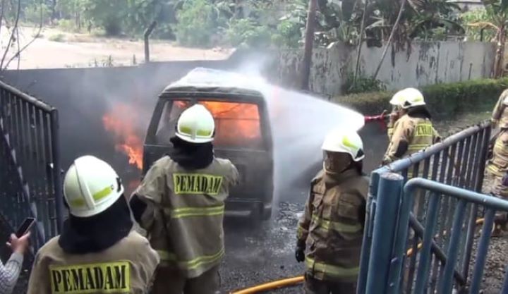 Sejumlah petugas Damkar memadamkan kobaran api yang membesar pada satu unit minibus yang membawa lima jerigen berisi Bahan Bakar Minyak (BBM) di tepi Jalan DI Panjaitan, Jatinegara, Jakarta Timur, Rabu (24/7/2024) siang. Foto: Joesvicar Iqbal/ipol.id