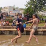 Suasana seru dua peserta lomba saling gebuk bantal dalam acara lomba bertajuk Semarak Kalimalang Hari Ulang Tahun (HUT) ke-79 RI di aliran Kalimalang di RW 04, Kelurahan Cipinang Melayu, Kecamatan Makasar, Jakarta Timur, pada Sabtu (24/8/2024). Foto: Joesvicar Iqbal/ipol.id