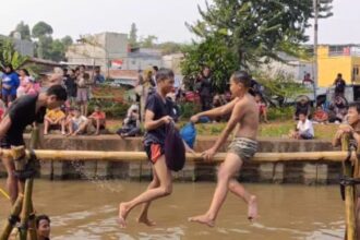 Suasana seru dua peserta lomba saling gebuk bantal dalam acara lomba bertajuk Semarak Kalimalang Hari Ulang Tahun (HUT) ke-79 RI di aliran Kalimalang di RW 04, Kelurahan Cipinang Melayu, Kecamatan Makasar, Jakarta Timur, pada Sabtu (24/8/2024). Foto: Joesvicar Iqbal/ipol.id