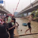 Peserta lomba titian bambu menjaga keseimbangan berjalan di atas pohon pinang dilumur oli agar tidak tercebur di aliran Kalimalang dalam lomba diadakan warga RW 04, Cipinang Melayu, Makasar, Jakarta Timur, pada Sabtu (24/8/2024) siang. Foto: Joesvicar Iqbal/ipol.id