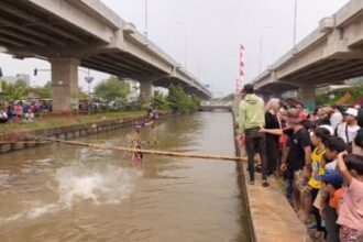 Suasana riuh penonton saat menyaksikan peserta lomba titian bambu tercebur di aliran Kalimalang dalam lomba diadakan warga RW 04, Cipinang Melayu, Makasar, Jakarta Timur, pada Sabtu (24/8/2024) siang-sore. Foto: Joesvicar Iqbal/ipol.id