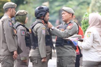 Kepala Satpol PP DKI Jakarta, Arifin memasangkan helm pada tim URC motor dalam pengamanan KTT Asean di Jakarta. Foto: Ist