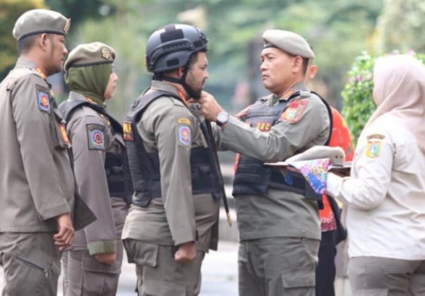 Kepala Satpol PP DKI Jakarta, Arifin memasangkan helm pada tim URC motor dalam pengamanan KTT Asean di Jakarta. Foto: Ist