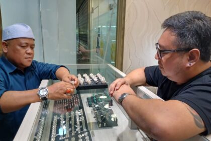 Pemilik Toko Jete Fine Jewelry, Billy Tanu (kaos hitam-kacamata) menunjukkan batu permata blue sapphire yang akan dipasang pada ring perak kepada Kepala Pasar Rawa Bening, Ahmad Subhan di Jatinegara, Jakarta Timur, pada Jumat (4/10/2024) siang. Foto: Joesvicar Iqbal/ipol.id