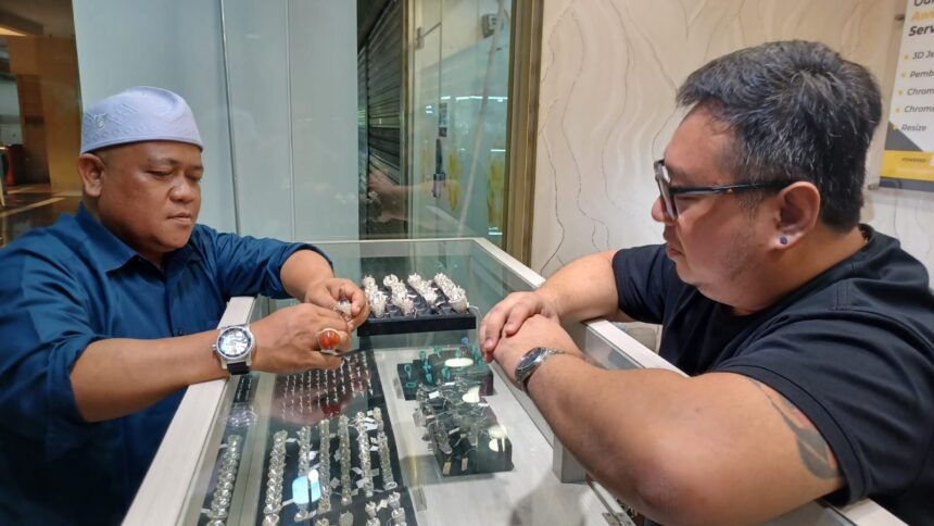 Pemilik Toko Jete Fine Jewelry, Billy Tanu (kaos hitam-kacamata) menunjukkan batu permata blue sapphire yang akan dipasang pada ring perak kepada Kepala Pasar Rawa Bening, Ahmad Subhan di Jatinegara, Jakarta Timur, pada Jumat (4/10/2024) siang. Foto: Joesvicar Iqbal/ipol.id