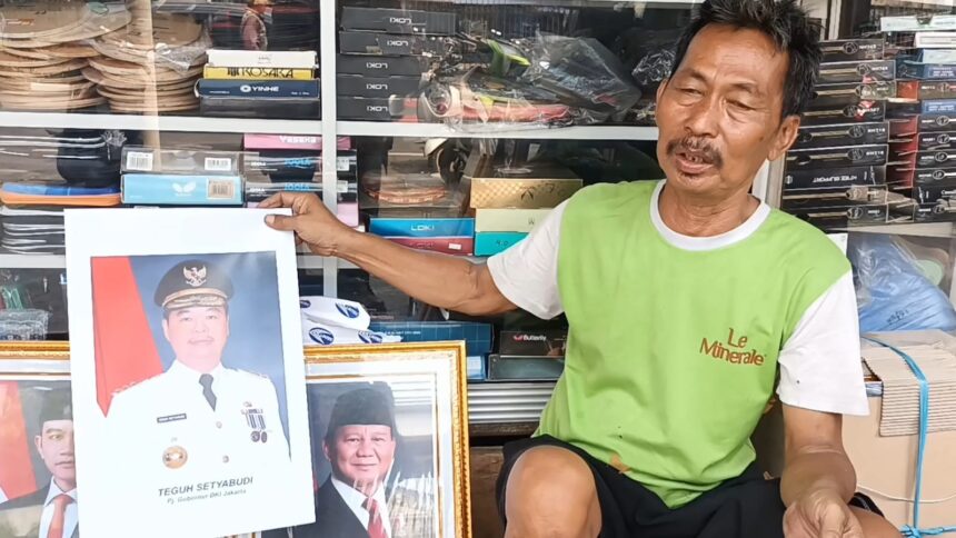 Pedagang foto frame, Kasbari menunjukkan bingkai foto Teguh Setyabudi yang resmi baru dilantik sebagai Penjabat (Pj) Gubernur DKI Jakarta di tokonya di kawasan Jatinegara, Jakarta Timur, Senin (21/10/2024). Foto: Joesvicar Iqbal/ipol.id