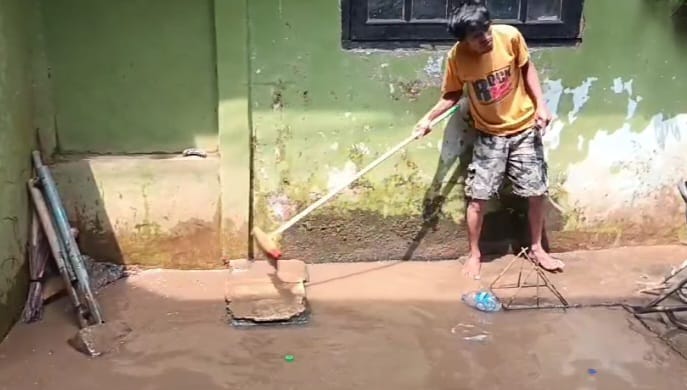 Seorang warga membersihkan lumpur sisa-sisa banjir yang masuk ke dalam rumah dan halaman di kawasan Kebon Pala, RW 04 dan RW 05, Kampung Melayu, Jatinegara, Jakarta Timur, Minggu (10/11/2024) siang. Foto: Ist