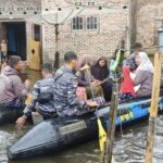 Prajurit Pangkalan TNI AL (Lanal) Tanjung Balai Asahan membantu warga menggunakan perahu karet menuju TPS dari rumahnya yang terendam banjir. Foto: Puspen TNI