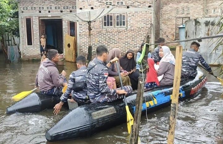 Prajurit Pangkalan TNI AL (Lanal) Tanjung Balai Asahan membantu warga menggunakan perahu karet menuju TPS dari rumahnya yang terendam banjir. Foto: Puspen TNI