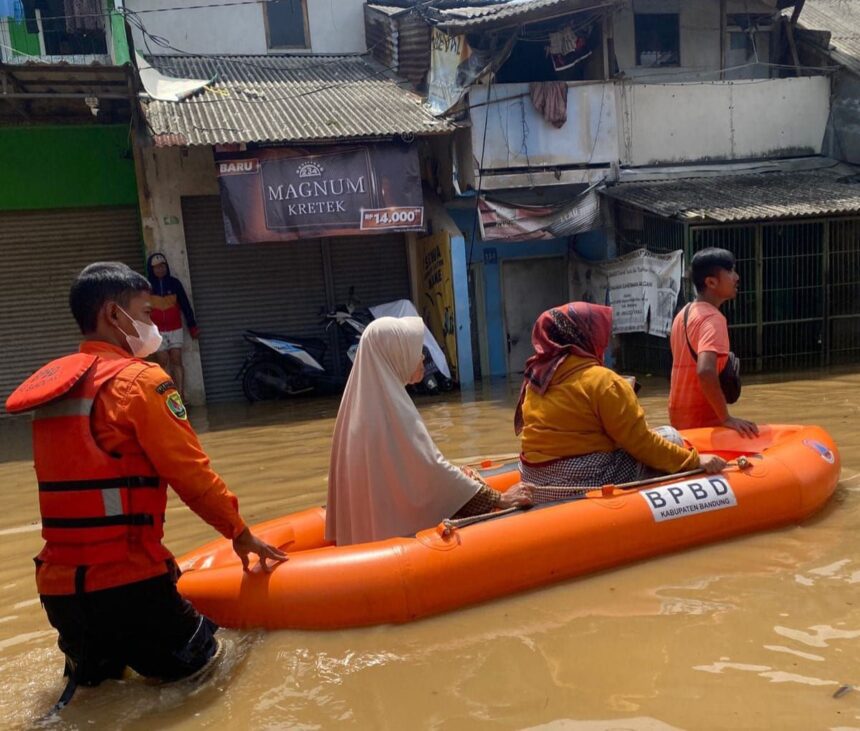 Petugas Badan Penanggulangan Bencana Daerah (BPBD) Kabupaten Bandung melakukan evakuasi Ibu-Ibu dengan perahu karet di wilayah Kota dan Kabupaten Bandung, Jawa Barat. Debit air Sungai Citarum meningkat dan meluap ke permukiman, Senin (25/11/2024). Foto: Ist