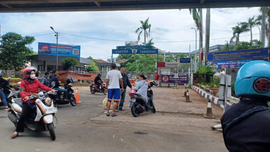 Sejumlah pengendara motor dan mobil yang ingin membayar pajak perpanjangan STNK sempat menunggu informasi dan juga yang langsung pergi di depan gerbang Samsat Jakarta Timur, pada Kamis (26/12/2024) siang. Foto: Joesvicar Iqbal/ipol.id