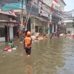 Warga bermain di jalan yang terendam banjir rob di kawasan Penjaringan Jakarta Utara