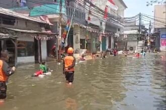 Warga bermain di jalan yang terendam banjir rob di kawasan Penjaringan Jakarta Utara