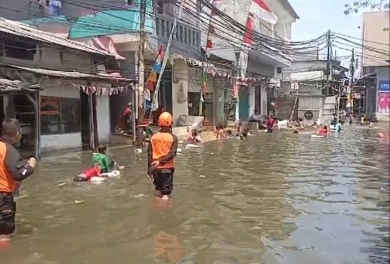 Warga bermain di jalan yang terendam banjir rob di kawasan Penjaringan Jakarta Utara