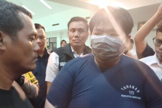 Anak bos toko roti, George Sugama Halim (baju tahanan biru) tersangka penganiaya pegawai saat dihadirkan dalam konferensi pers di Mapolres Metro Jakarta Timur, Senin (16/12/2024) sore. Foto: Joesvicar Iqbal/ipol.id