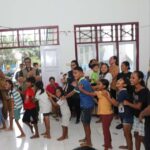 Suasana pelaksanaan psikosial kepada anak-anak yang dihadiri oleh Deputi Bidang Sistem dan Strategi Badan Nasional Penanggulangan Bencana (BNPB), Raditya Jati (rompi dan kemeja hijau) di SD Inpres 25 Tongute Goin, Halmahera Barat, Maluku Utara, pada Selasa (21/1/2025). Foto: Ist