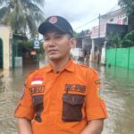 Komandan Regu B Badan Penanggulangan Bencana Daerah (BPBD) Korwil Jakarta Timur, Abu melaporkan dari lokasi banjir permukiman warga di RT 04/RW 06, Kelurahan Cakung Barat, Kecamatan Cakung, Jakarta Timur, pada Rabu (29/1/2025). Foto: Joesvicar Iqbal/ipol.id