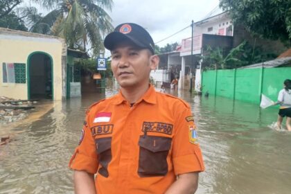 Komandan Regu B Badan Penanggulangan Bencana Daerah (BPBD) Korwil Jakarta Timur, Abu melaporkan dari lokasi banjir permukiman warga di RT 04/RW 06, Kelurahan Cakung Barat, Kecamatan Cakung, Jakarta Timur, pada Rabu (29/1/2025). Foto: Joesvicar Iqbal/ipol.id