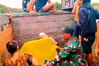 Babinsa Koramil 1201-03/Mempawah Hilir, Kodim 1201/Mempawah Sertu Amirudin saat membantu persalinan ibu hamil yang terjebak banjir di truk. Foto: Dispenad