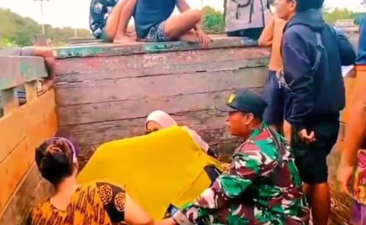 Babinsa Koramil 1201-03/Mempawah Hilir, Kodim 1201/Mempawah Sertu Amirudin saat membantu persalinan ibu hamil yang terjebak banjir di truk. Foto: Dispenad