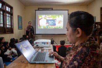 Guru Pasraman yang ada di Desa Ngadiwono, Tosari, Pasuruan, Jawa Timur, sedang mengajar menggunakan media laptop dan proyektor yang baru saja didapat dari pemberian hibah NeutraDC melalui program CSR, Two Hands Hub NeutraDC. Foto: Telkom Indonesia