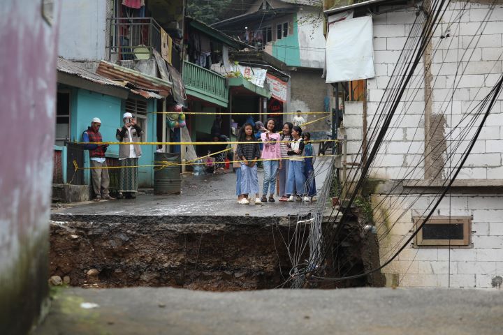 Sejumlah warga beraktivitas di dekat lokasi jembatan yang ambles dampak banjir bandang di Desa Tugu Selatan, Kecamatan Cisarua, Kabupaten Bogor, Jawa Barat, pada Selasa (4/3/2025). Foto: Ist