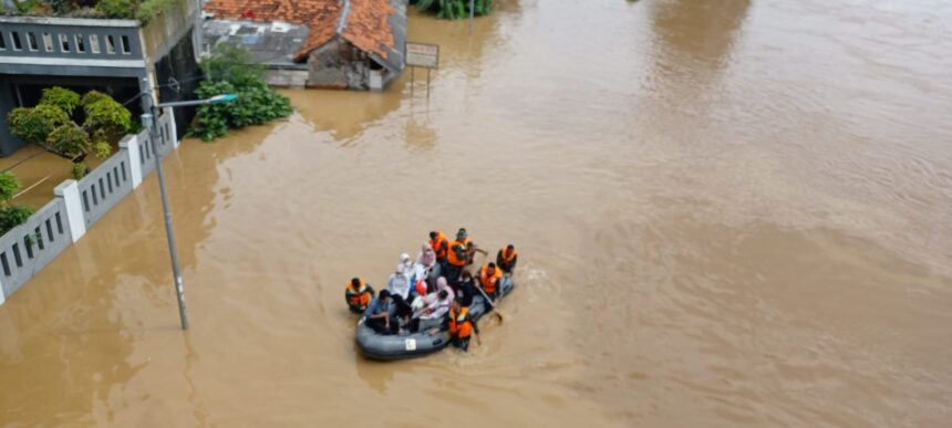 Petugas Badan Nasional Penanggulangan Bencana (BNPB) dan Badan Penanggulangan Bencana Daerah (BPBD) Kota Jakarta Timur menggunakan perahu karet mengevakuasi warga RT 1 hingga RT 13 dan 14, Cililitan, Kramat Jati, yang terjebak banjir, Selasa (4/3/2025). Foto: Joesvicar Iqbal/ipol.id