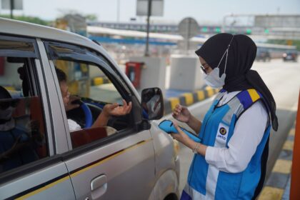 Ilustrasi petugas jalan tol tengah mencoba membantu proses pembayaran pengendara mobil di gerbang tol.