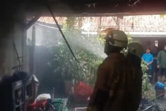 Dua petugas Damkar berupaya memadamkan api di unit garasi rumah milik Surya Toto di kawasan Berlan Jalan Ksatrian IX, RT 3 RW 3, Kebon Manggis, Matraman, Jakarta Timur, pada Minggu (16/3/2025) sekitar pukul 16.46 WIB. Foto: Ist