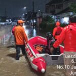 Petugas tengah membantu warga banjir di Taman Mangu Pondok Aren.