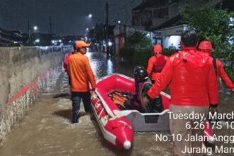 Petugas tengah membantu warga banjir di Taman Mangu Pondok Aren.