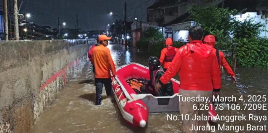 Petugas tengah membantu warga banjir di Taman Mangu Pondok Aren.