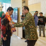 General Manager Hotel THE 1O1 Jakarta Sedayu Dharmawangsa, Garna Sobhara Swara (kanan) menyebatkan Cukin jingga bermotif adat Betawi kepada Camat Kebayoran Baru, Achmad Basyaruddin. (Alidrian Fahwi/ipol.id)