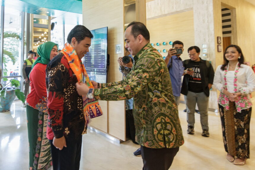 General Manager Hotel THE 1O1 Jakarta Sedayu Dharmawangsa, Garna Sobhara Swara (kanan) menyebatkan Cukin jingga bermotif adat Betawi kepada Camat Kebayoran Baru, Achmad Basyaruddin. (Alidrian Fahwi/ipol.id)
