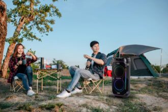 Dua anak muda bersantai sambil menikmati alunan musik dengan menggunakan portable party speaker Sharp