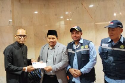 Chief Operating Officer BPKH Limited, Iman Ni’matullah, menyerahkan dana kompensasi kepada jamaah haji yang tidak mendapat makanan. Foto: Kemenag