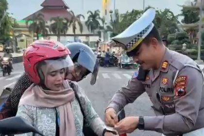 Momen menjelang HUT RI ke-80, Kasat Lantas Polres Kudus, AKP Royke N Darean dan jajaran Satlantas Polres Kudus membagikan dan memasangkan sejumlah bendera merah putih ke unit pengendara roda dua dan roda empat di sekitar kantor Bupati Kudus, Kamis (7/8/2025). Foto: Ist