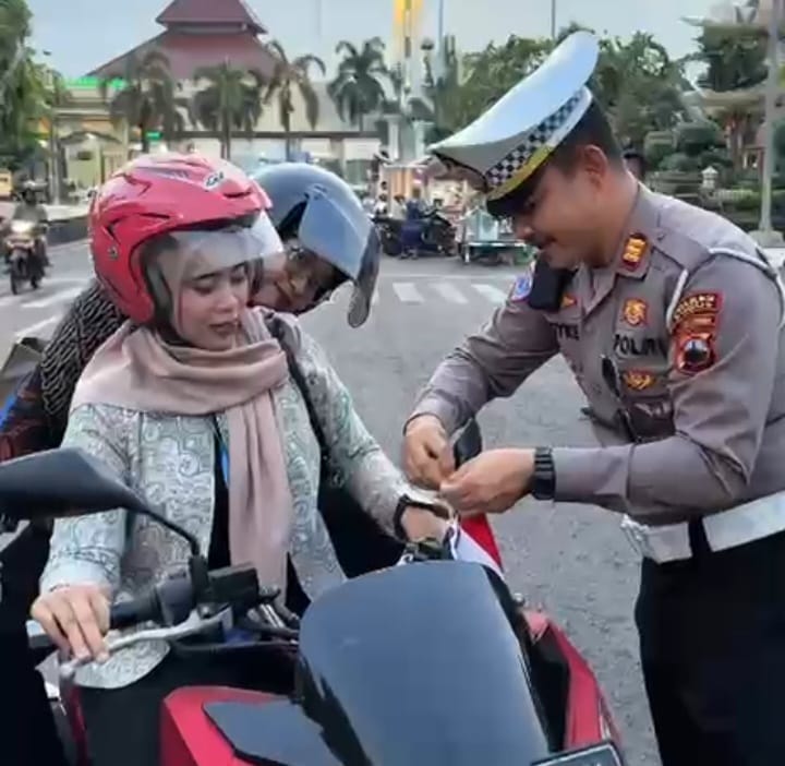 Momen menjelang HUT RI ke-80, Kasat Lantas Polres Kudus, AKP Royke N Darean dan jajaran Satlantas Polres Kudus membagikan dan memasangkan sejumlah bendera merah putih ke unit pengendara roda dua dan roda empat di sekitar kantor Bupati Kudus, Kamis (7/8/2025). Foto: Ist