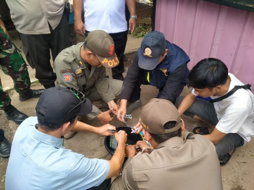 Sejumlah petugas gabungan, Satuan Polisi Pamong Praja (Satpol PP) Kelurahan Ciganjur, Kecamatan Jagakarsa, Jakarta Selatan, memusnahkan langsung temuan obat-obatan terlarang dijual bebas oleh pedagang kios pulsa di Jalan Brigif Raya, RT 012 RW 06, Ciganjur, Jagakarsa, Rabu (20/8/2025) siang. Foto: Joesvicar Iqbal/ipol.id