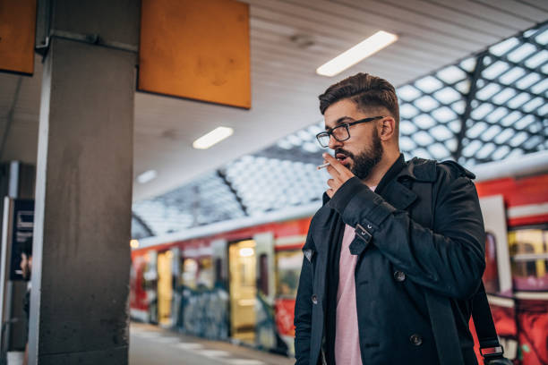 Ilustrasi, Pemuda berdiri di stasiun kereta api dan merokok. Foto: Istock @South_agency