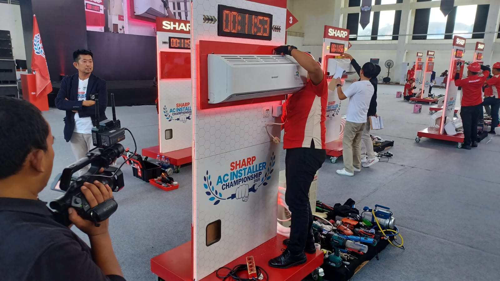 Ajang Bergengsi Sharp AC Installer Championship 2025 Diikuti 1.080 Peserta Se-Indonesia, 20 Finalis Ngadu Skill di Gedung Judo Kelapa Gading 2 Presiden Direktur PT Sharp Electronics Indonesia, Shinji Teraoka, saat mengamati dan menyaksikan tim juri melakukan penilaian langsung 20 teknisi installer AC terbaik unjuk gigi dalam grand final Sharp AC Installer Championship 2025 di Gedung Judo, Kelapa Gading, Jakarta Utara, Minggu (21/9/2025). Foto: Joesvicar Iqbal/ipol.id
