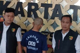 Tersangka M Andre, 29, dengan tangan diborgol dihadirkan dalam konfrensi pers pengungkapan kasus suami bakar isteri dan penganiayaan Ibu mertua di Mapolres Metro Jakarta Timur, Senin (22/9/2025). Foto: Joesvicar Iqbal/ipol.id