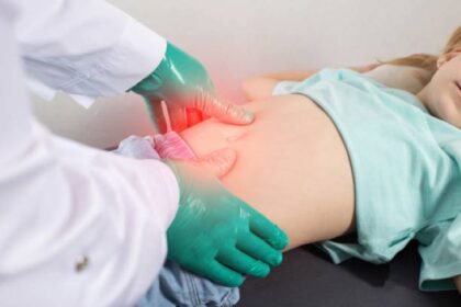 Ilustrasi, Tangan dokter dengan sarung tangan hijau menyelidiki perut seorang gadis kecil yang mengalami kembung dan nyeri perut akibat keracunan makanan. Foto: Istcok @Henadzi Pechan